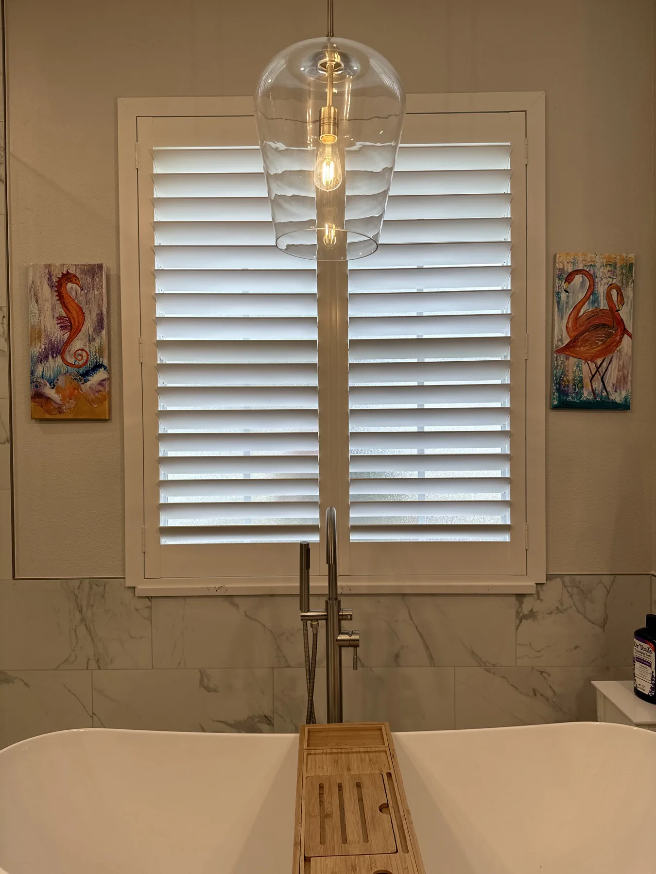 White plantation shutters installed above a freestanding bathtub