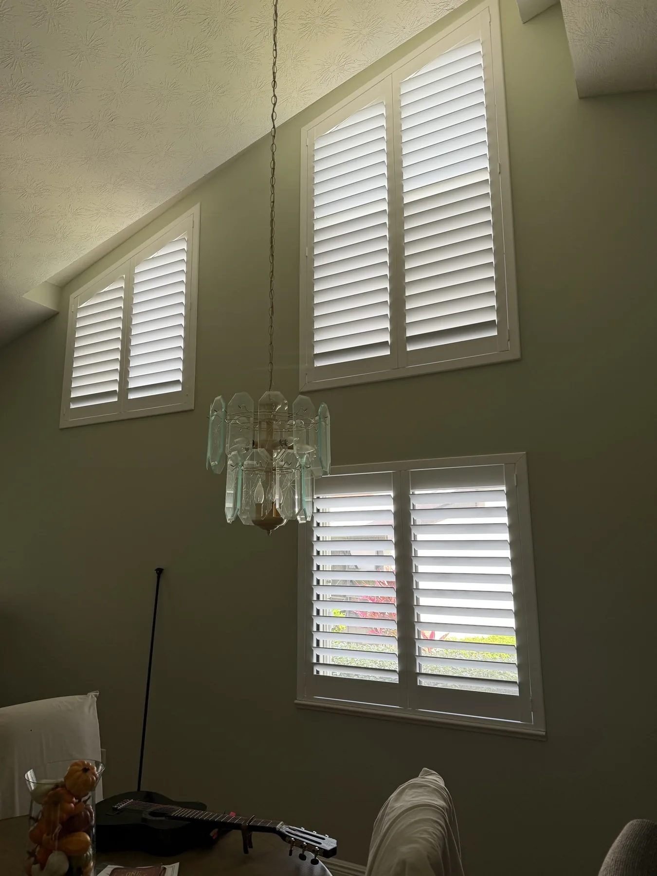 Custom plantation shutters fitted to tall angled windows beneath a vaulted ceiling