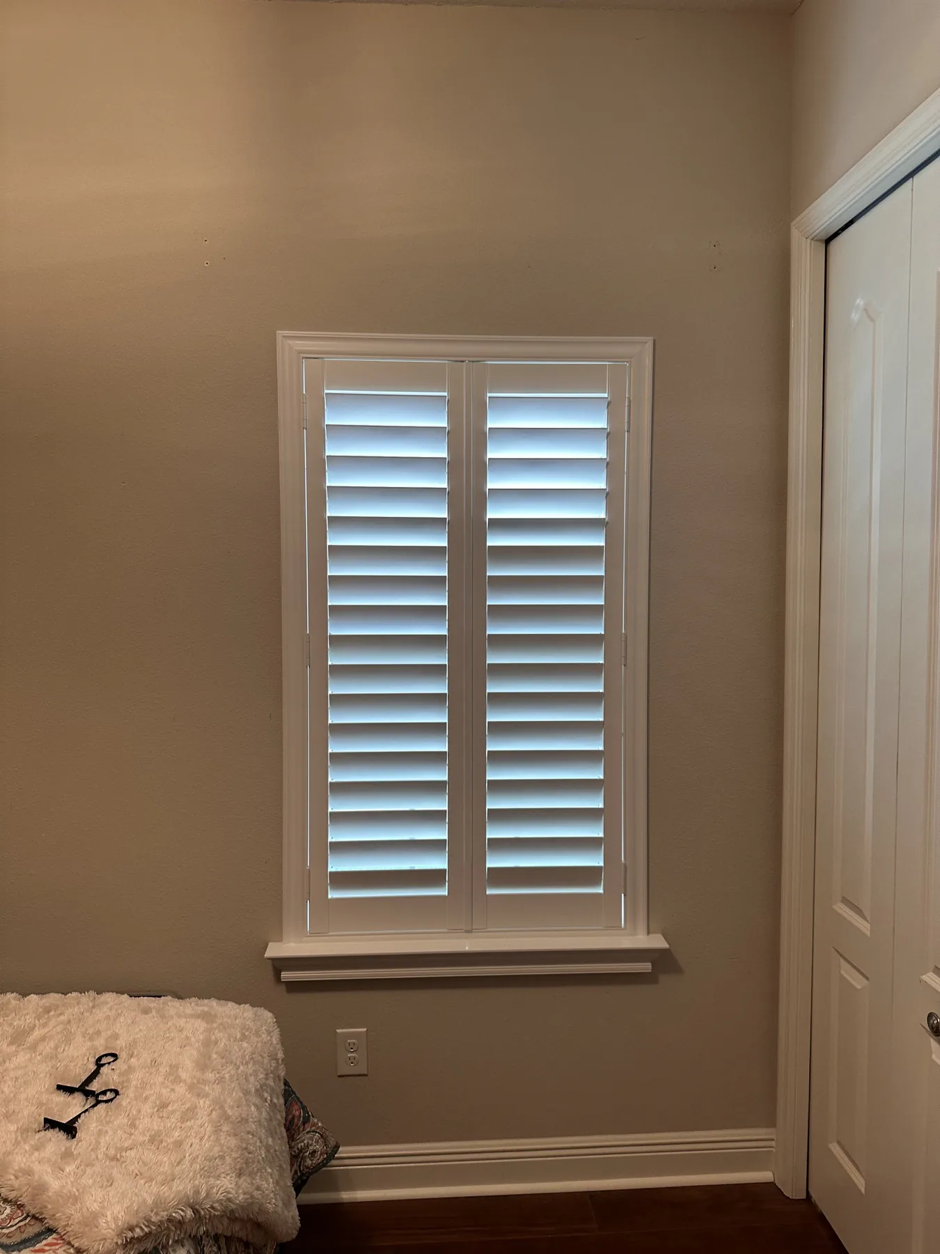 White plantation shutters installed on a narrow bedroom window