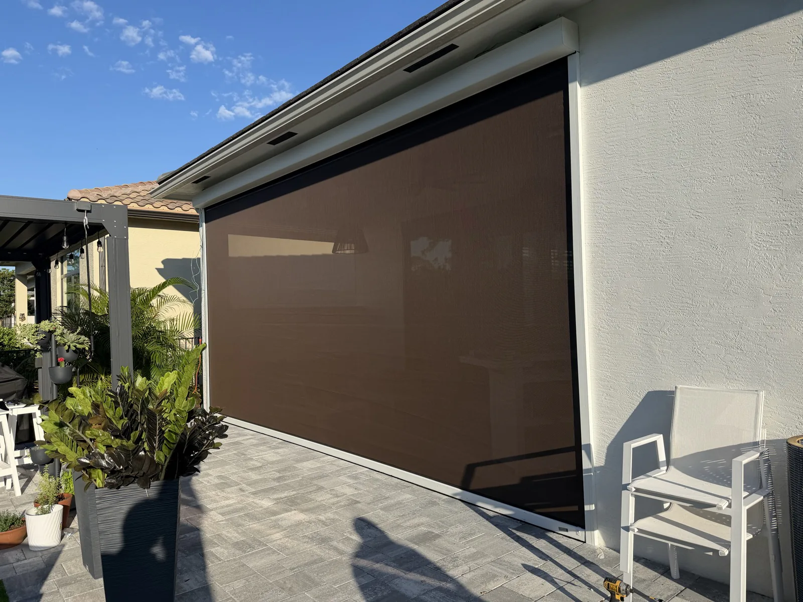Brown exterior screen fitted across a patio opening beside a garden