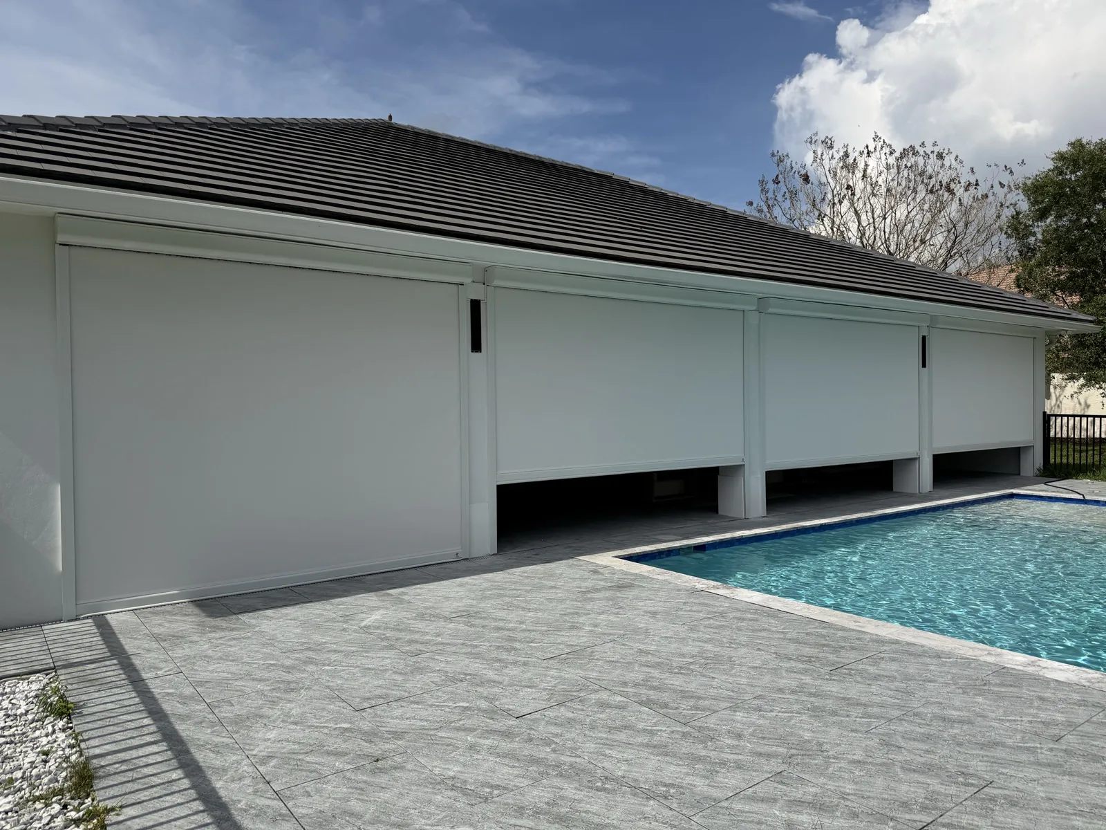 White roll-down screens enclosing a covered patio beside a swimming pool