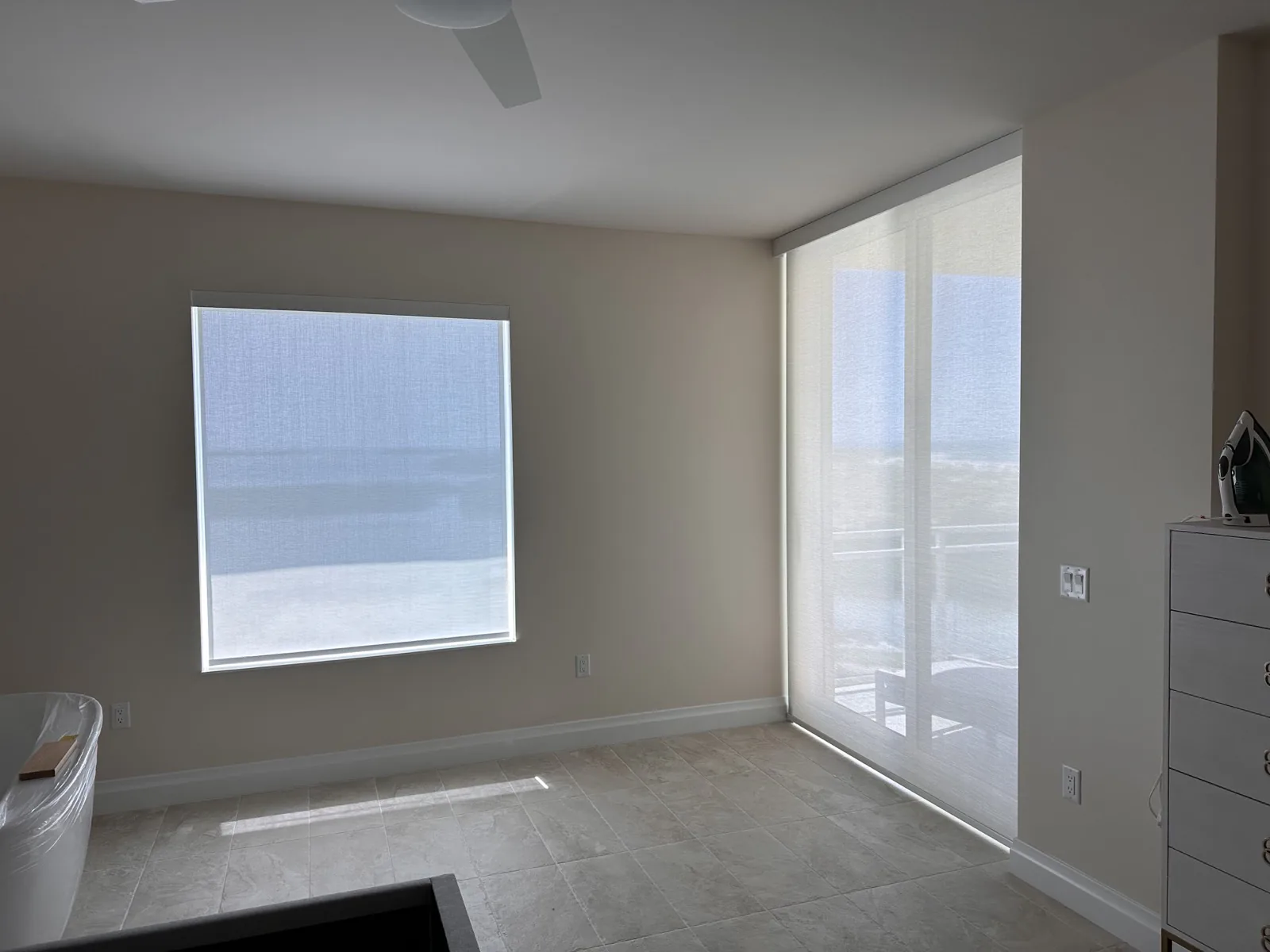 Solar shades installed over a bedroom window and sliding door