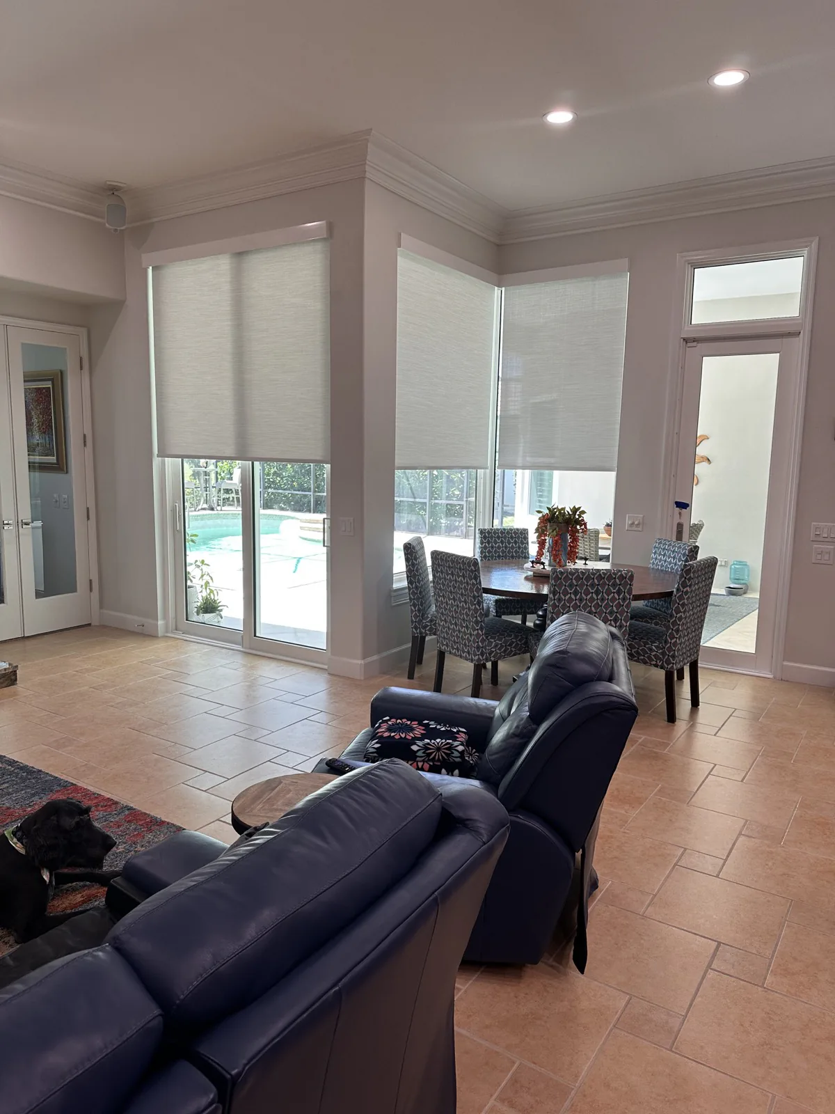 Custom roller shades in a bright poolside living and dining room