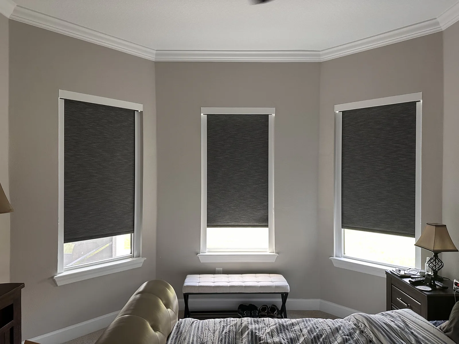 Dark roller shades installed in a bedroom bay window