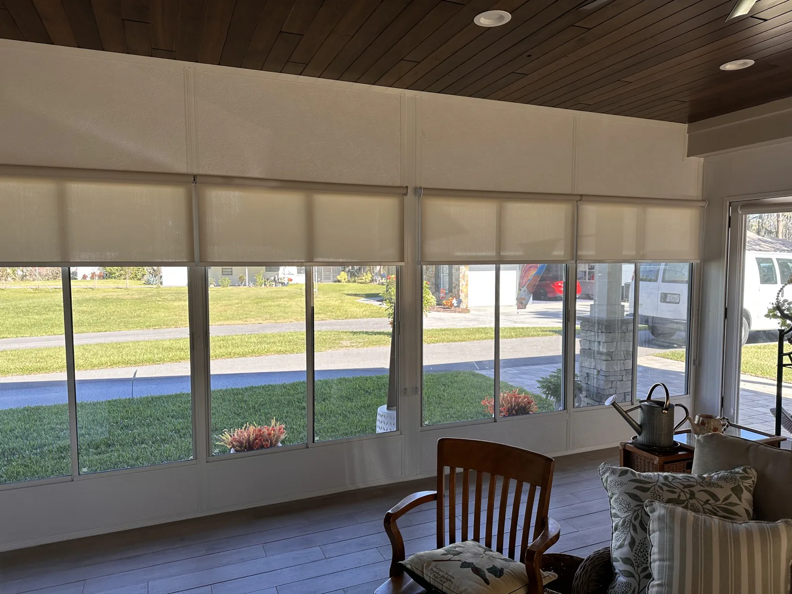 Light-filtering roller shades across a sunroom wall of windows